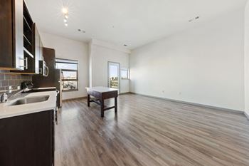 an empty living room and kitchen with wood floors and white walls